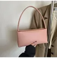 Close-up of minimalist pink baguette bag held by a person in a stylish suit - Pink