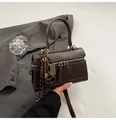 Dark brown leather top-handle pillow bag with vintage metal charms on a grey suit - With Ornament / Brown