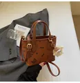 Brown leather tote bag with butterfly patterns and plush keychain on grey suit backdrop - With Ornament / Brown