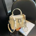 Minimalist white leather bucket bag with top handle and silver bell pendant on a chair - With Pendant / Off White