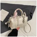 Close-up of cream Boston bag with embossed letters, lace bow, and silver heart charm - With Pendant / White