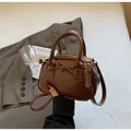Detail of a dark brown mini Boston bag featuring a stylish bow and smooth faux leather finish - Brown