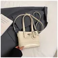 Detail of cream quilted handbag with twist-lock closure and pearl bow charm detail - With Ornament / Off White