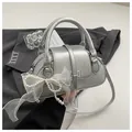 Detailed macro view of silver Boston bag with leather texture and white bow decoration - With Ornament / Silver