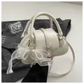 Macro detail of creamy white PU leather Boston bag with pearl mesh bow and silver hardware - With Ornament / White