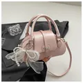 Detail of pink faux leather pillow bag with pearl bow charm and adjustable strap - With Ornament / Pink