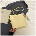 Minimalist light yellow bucket shoulder bag in matte faux leather with a cute doll pendant - With Ornament / Yellow
