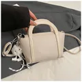 Borsa a secchiello beige crema con grana litchi, doppi manici e ciondolo peluche - bianco con ciondolo