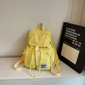 Minimalist light yellow nylon backpack with white buckle closure and brand label - Yellow