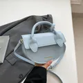 Bolso de mano de media luna azul claro con asa anudada y textura de cuero lichi - Azul
