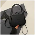 Minimalist black lychee leather crossbody bag with round handle and adjustable strap - Black