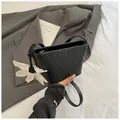 Black woven bucket shoulder bag with white flower charm and slim strap for women - Black