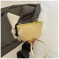 Sac seau tissé jaune pâle avec breloque fleur blanche sur une veste de costume grise - Jaune