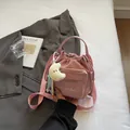 Pink nylon drawstring crossbody bag with decorative charms and adjustable shoulder strap - With Ornament / Pink