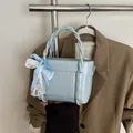 Light blue bucket bag with woven handle and blue checkered bow accessory for women - Blue