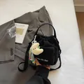 Black nylon drawstring bucket bag featuring a yellow moon plush pendant and shoulder strap - With Ornament / Black