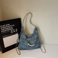 Blue denim underarm bag with silver butterfly buckle and decorative pearl chain detail - Denim Blue