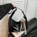 Bolso hobo negro brillante con cinta de encaje blanco y colgante de corazón en sofá - Negro Con Colgante