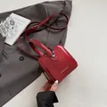 Mini red patent leather box bag with crossbody strap and glossy finish shown on suit - Red
