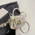 Elegante cremefarbene Satteltasche mit Webstruktur, Goldverschluss und Perlenanhängern - Mit Anhänger / Weiß