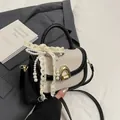 Elegante gewebte Satteltasche in Beige und Schwarz mit dekorativer Spitzenschleife - Mit Anhänger / Schwarz