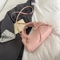 Borsa tote rosa con fiocchi e tracolla su un letto con un blazer grigio elegante - Rosa Senza Pendente