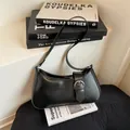 Minimalist black leather baguette shoulder bag with silver buckle on a lifestyle background - Black