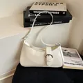 Minimalist white glossy baguette shoulder bag with a silver buckle on a textured base - White