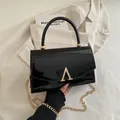 Sac bandoulière élégant en cuir verni noir avec boucle en A dorée et bandoulière chaîne - Noir