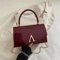 Sac à main en cuir verni rouge foncé avec fermoir doré en A et bandoulière chaîne - Rouge