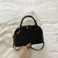 Klassische schwarze Muschelhandtasche mit geometrischem Muster und Gold-Hardware - Schwarz