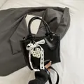 Elegante borsa nera verniciata con fiocco in pizzo bianco e ciondolo a cuore di perle - Nero