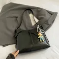 Minimalist black PU tote bag with pearl strap and cute doll charm on grey blazer - Black With Pendant