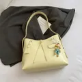Pale yellow PU leather tote bag with pearl doll charm and logo tag on grey suit - Yellow with Pendant