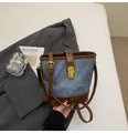 Dettaglio borsa a secchiello in denim con finiture in pelle, chiusura dorata e tracolla - Blu