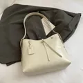 Minimalist off-white leather tote bag with glossy finish and decorative strap charm - White Without Charm