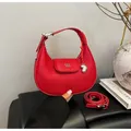 Chic red crescent handbag with lychee texture and heart charm in a hand-held display - Red