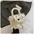 Close-up of white leather handbag with belt buckle detail and cute plush bear charm - White with Pendant