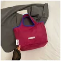 Detail of hot pink nylon tote bag with blue trim and white woven brand label - Burgundy