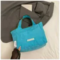 Detail of blue nylon tote bag showing double brand labels and contrast green trim - Blue