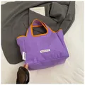 Close-up of purple nylon tote with orange trim and branded woven label on fabric - Purple