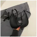Bolso medialuna negro con textura de lichi y detalle de herraje plateado minimalista - Negro