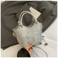 Detalle de bolso plateado con estampado de serpiente, asa anudada y aros dorados - Con Ornamento / Plateado