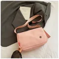 Detailed view of pink nylon crossbody bag with adjustable strap on stylish suit background - Pink
