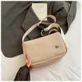 Close-up of beige mesh crossbody bag texture with wide fabric strap on white sheet - Off White