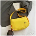 Detail of a bright yellow nylon crossbody bag with adjustable strap and metal badge - Yellow