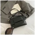 Detalle del bolso de hombro en cuero negro con hebillas doradas y correa ajustable - Negro