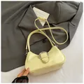 Elegante borsa a mezzaluna giallo crema con fibbia argento su sfondo abito scuro - Giallo