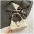 Elegante borsa a mezzaluna bianco sporco con finiture argento su un blazer grigio - Bianco