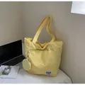 Close-up of yellow nylon tote bag featuring front pockets and a round coin purse - Yellow